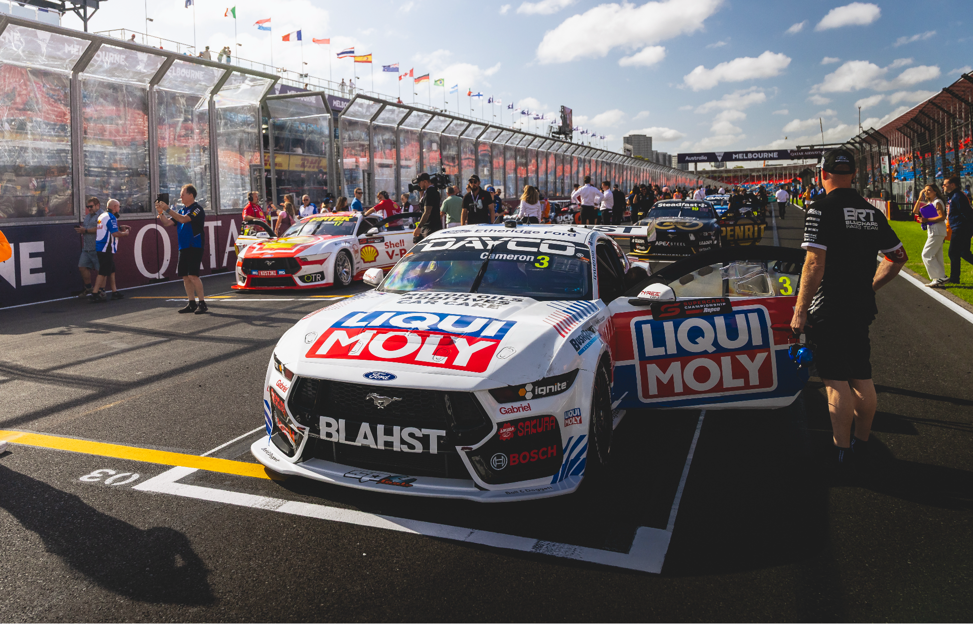 Race car on a track with 'Liqui Moly' branding, surrounded by spectators and other cars.